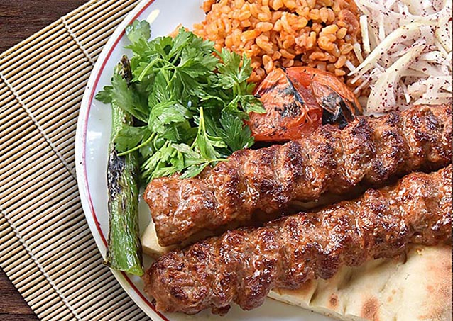 Delicious Adana kebab served with grilled vegetables and rice